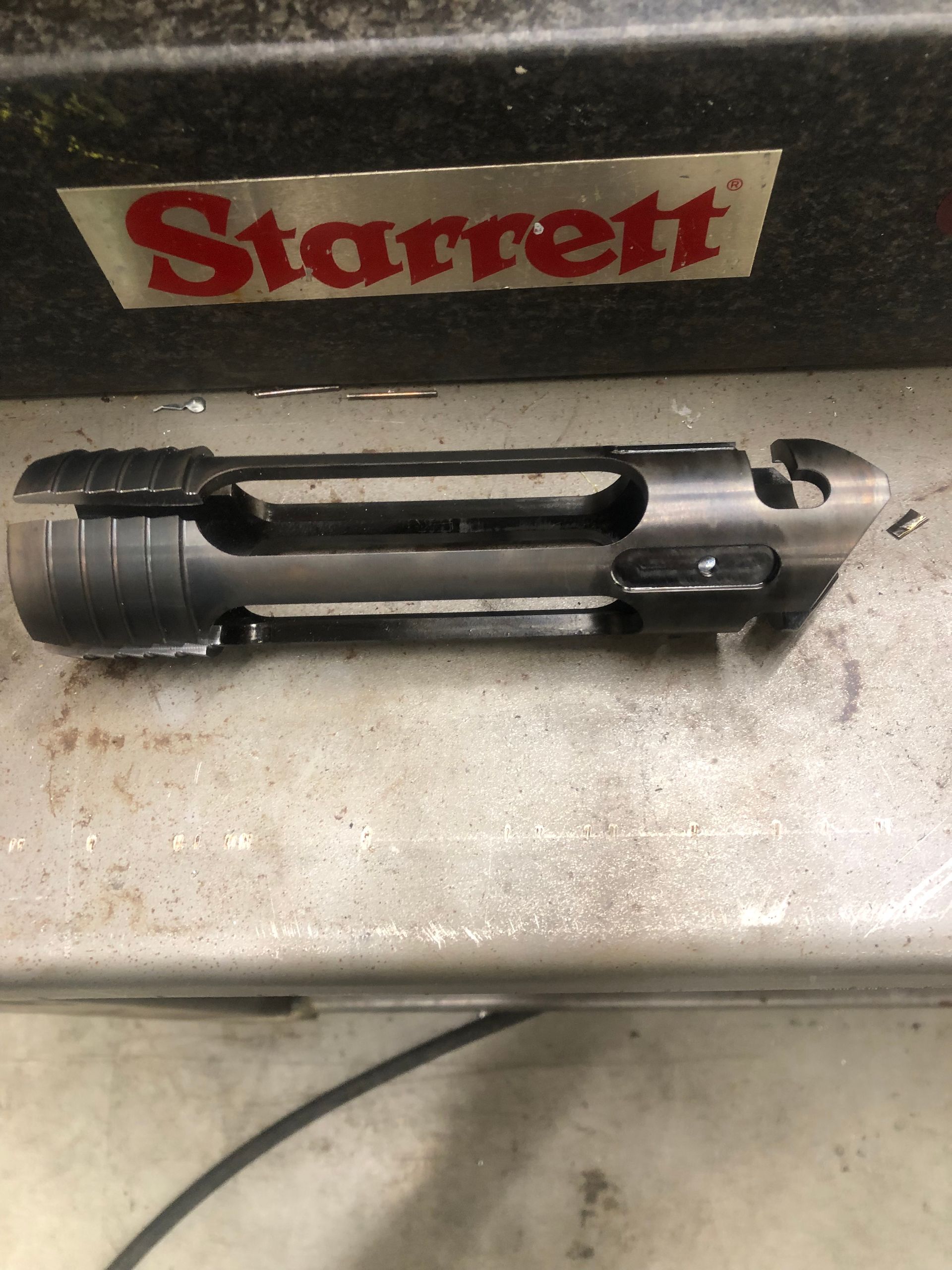 Black metal tool part on a workbench beneath a red Starrett sign.