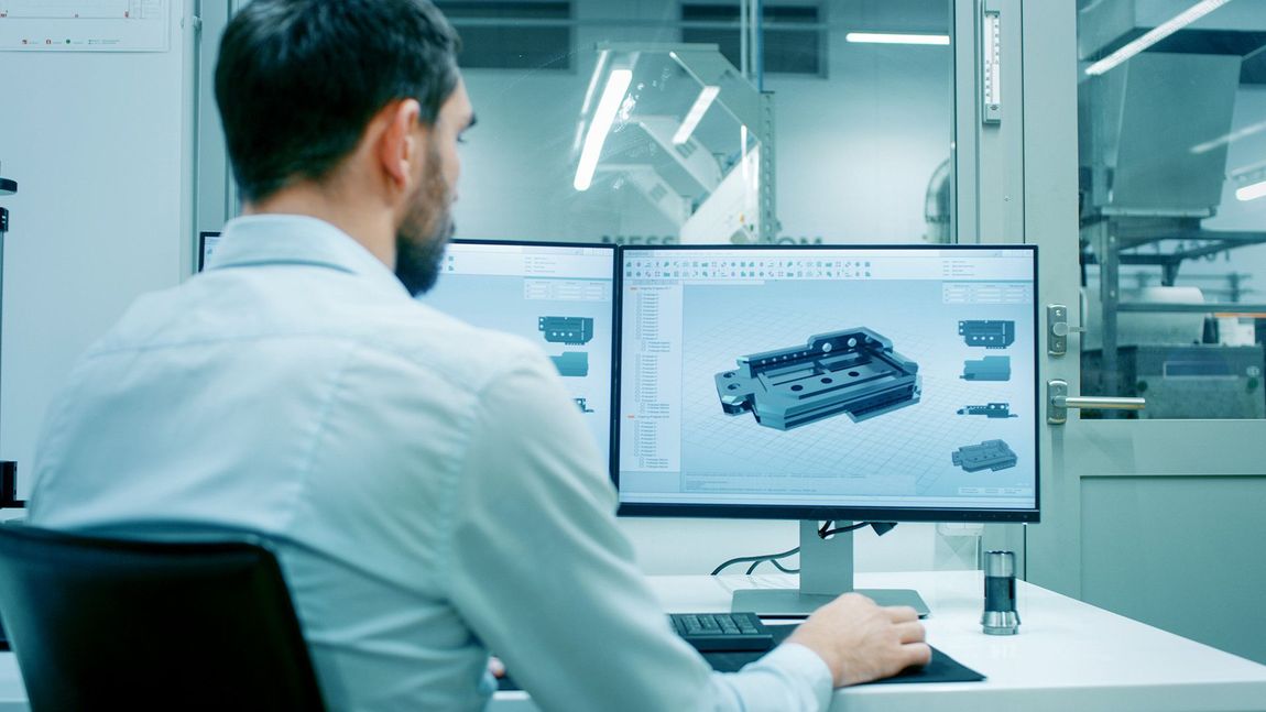 Engineer viewing a 3D car model on dual monitors in a modern lab workspace
