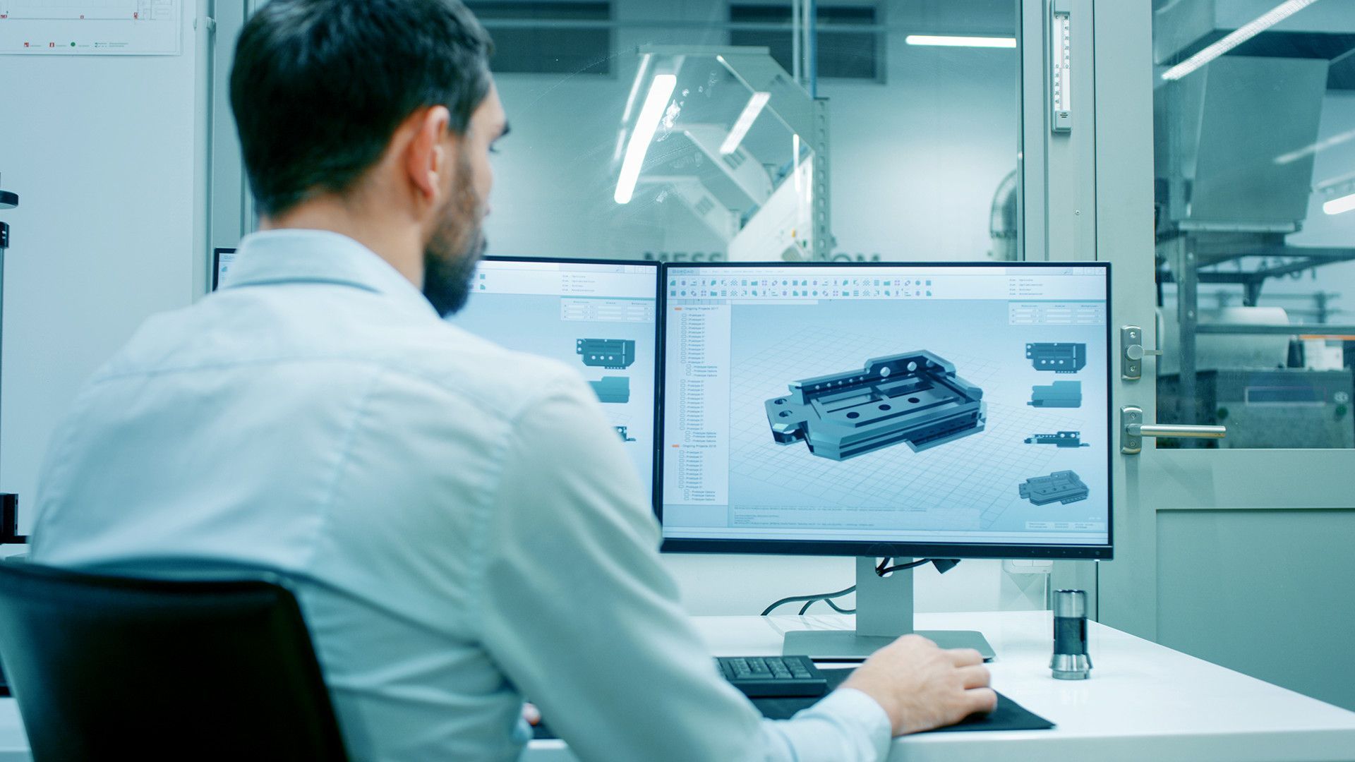 Engineer viewing a 3D car model on dual monitors in a modern lab workspace