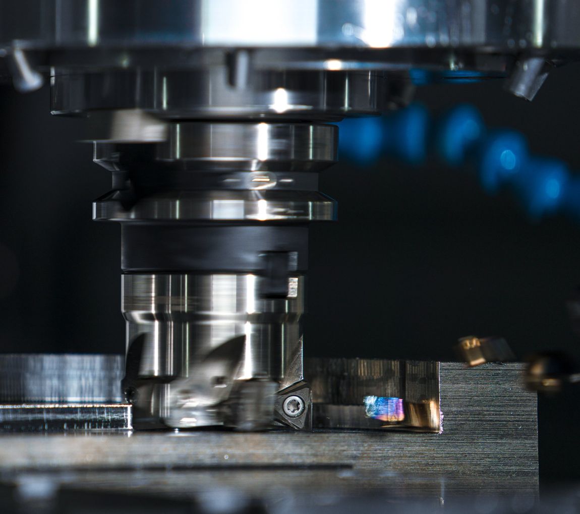 CNC milling machine cutting metal, with a rotating tool over a clamped workpiece.