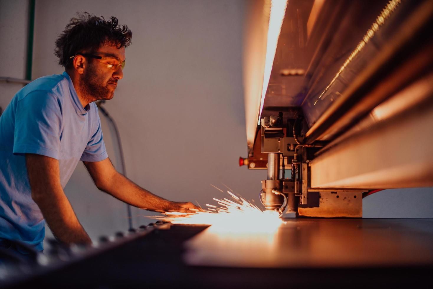 Worker operating a welding machine, with bright sparks in an industrial workshop